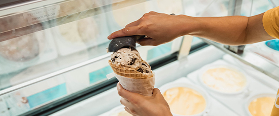 An employee making an ice cream waffle cone